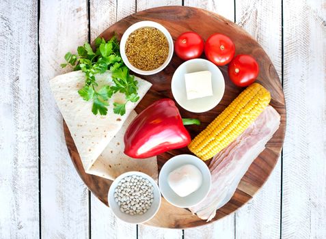 Ingredients for cooking Mexican Quesadilla wrap with vegetables, corn, sweet pepper and sauces on the parchment and table. horizontal view.