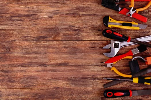 This is an overhead photo of construction tools and brush with copy space on a wood background. There is a lot of space