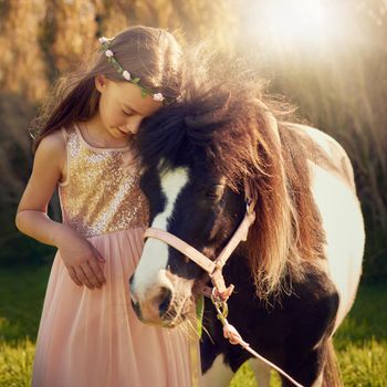 Shot of a cute little girl playing with her pony outside.
