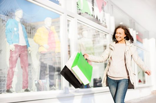 Happy young woman with bags doing shopping at the city center