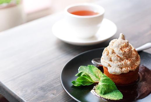 Breakfast time . Tea and cake with cream, garnished with mint leaves