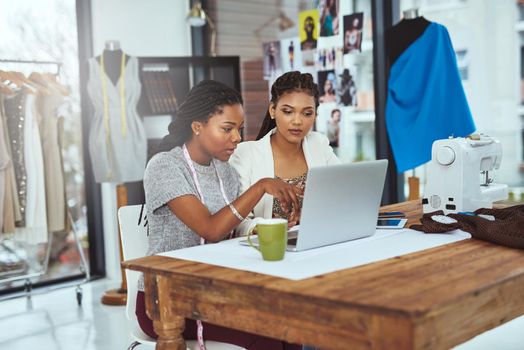 Cropped shot of two young fashion designers working on a laptop.