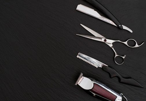 Barber shop equipment on Black background with place for text. Professional hairdressing tools. Comb, scissor, clippers and hair trimmer isolated.