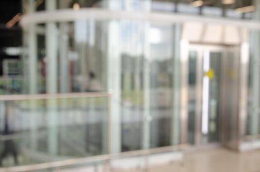 Office building or university library lobby hall reading area blur background with blurry school hallway corridor interior view to empty corridor entrance, glass wall and exterior light illumination