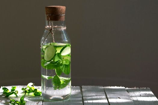 Nutritious detox water or emonade with cucumber and mint on wooden table. Copy space for text.