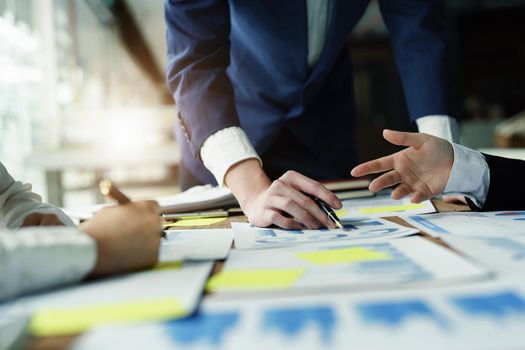 Male businessman pointing to take summarizing marketing strategy documents with female colleagues in meeting, teamwork, investment planning.