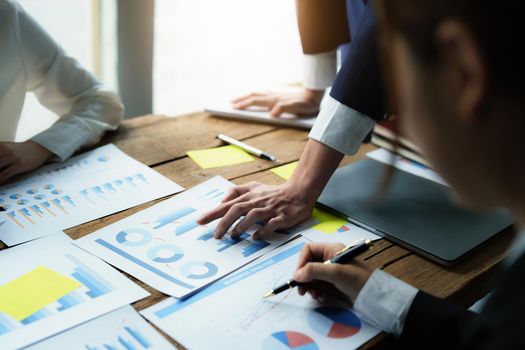 Male businessman pointing to take summarizing marketing strategy documents with female colleagues in meeting, teamwork, investment planning.