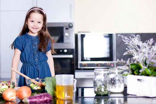 little daughter cooking in the kitchen at home. Girl Assisting In Preparing Food - Stock image