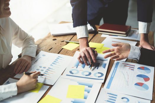 Male businessman pointing to take summarizing marketing strategy documents with female colleagues in meeting, teamwork, investment planning.