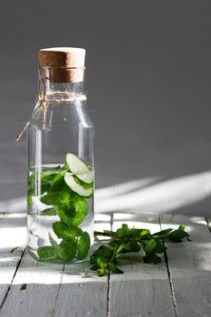 Nutritious detox water or emonade with cucumber and mint on wooden table