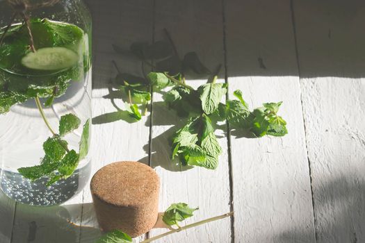 Nutritious detox water or emonade with cucumber and mint on wooden table