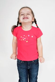 Happy toddler girl having a great time and laughing. Isolated on grey.