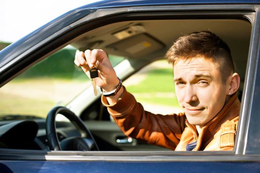 Man sitting inside car and showing keys to new car