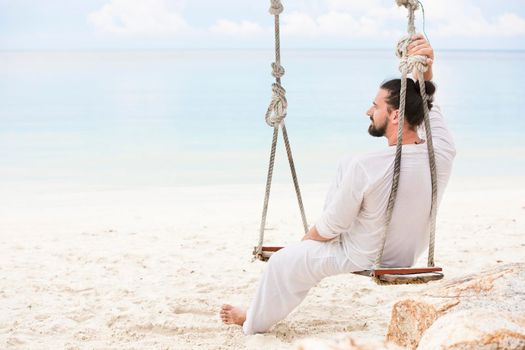 Businessman wearing white freelance sitting on beach swing and dreaming