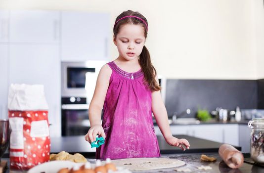 little daughter cooking in the kitchen at home. Girl Assisting In Preparing Food - Stock image