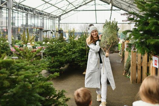 Mother and kids buying a Christmas tree in the market.