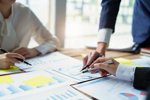 Male businessman pointing to take summarizing marketing strategy documents with female colleagues in meeting, teamwork, investment planning.