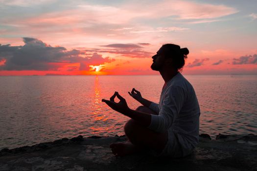 Yoga scene man silhouette in sunset background.