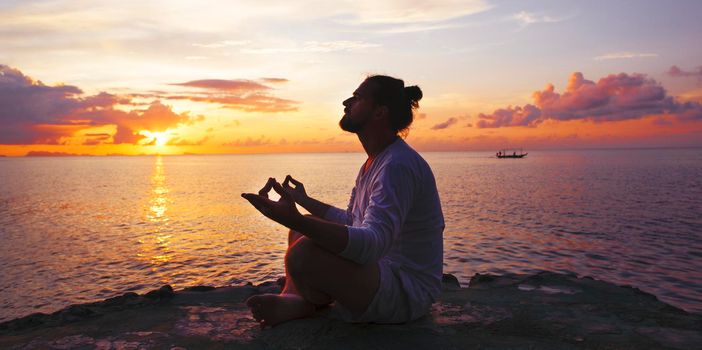 Yoga scene man silhouette in sunset background.