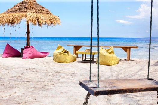 Straw umbrellas and bean bag at the seashore.