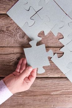 Incomplete puzzles lying on wooden rustic boards. Conceptual of innovation, solution finding and integration. Hand with puzzle piece