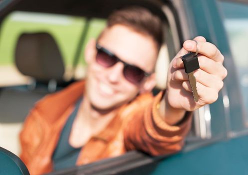 Man sitting inside car and showing keys to new car