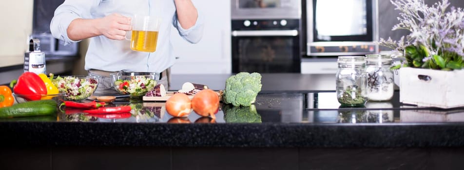 Handsome man cooking at home preparing salad in kitchen.