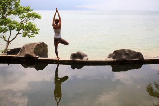 Woman practicing or doing morning meditation Yoga in nature at the beach