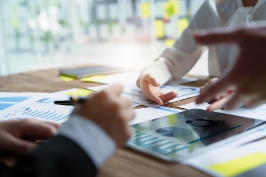 Male businesswoman pointing to tablet monitor summarizing marketing strategy with female colleagues in meeting, teamwork, investment planning.