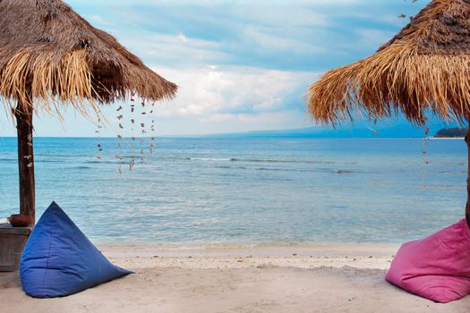 Straw umbrellas and bean bag at the seashore.