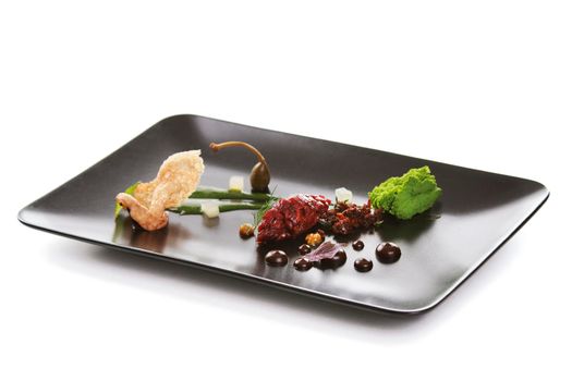 Molecular modern cuisine. Chips Pigskin with tartare or carpaccio of beef. Stock image. Isolated on white.