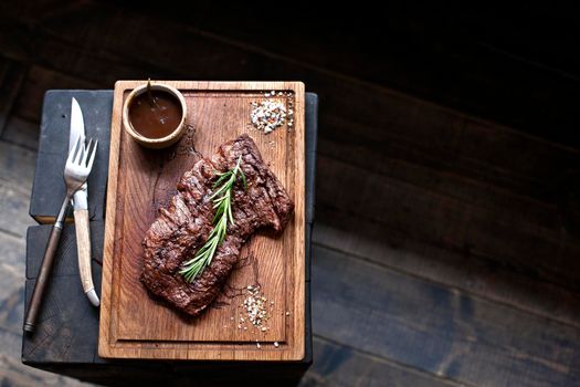 Beef steak. Piece of Grilled BBQ beef marinated in spices and herbs on a rustic wooden board over rough wooden desk with a copy space. Top view