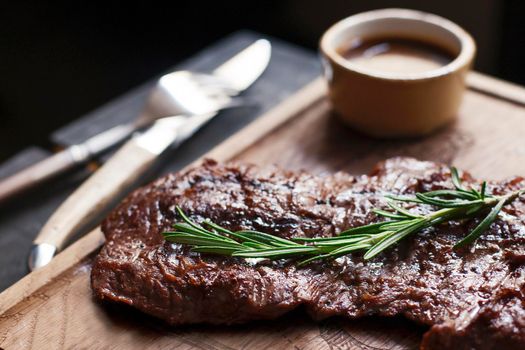 Beef steak. Piece of Grilled BBQ beef marinated in spices and herbs on a rustic wooden board over rough wooden desk with a copy space. Top view. Stock Image