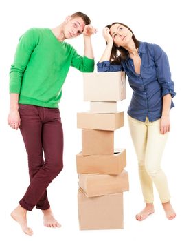 Young couple smile while holding large cardboard boxes. Vertical shot. Isolated on white.