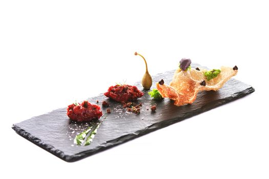 Molecular modern cuisine. Chips Pigskin with tartare or carpaccio of beef. Stock image. Isolated on white.