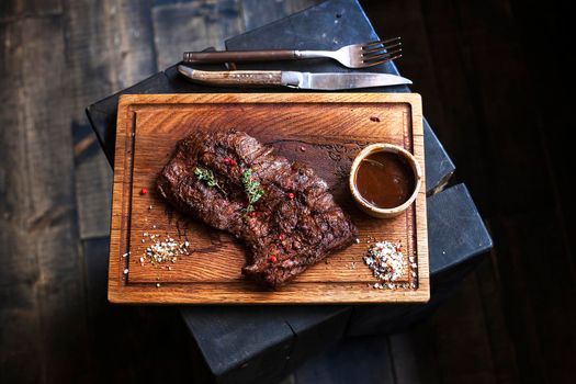 Beef steak. Piece of Grilled BBQ beef marinated in spices and herbs on a rustic wooden board over rough wooden desk with a copy space. Top view