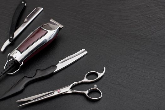 Barber shop equipment on Black background with place for text. Professional hairdressing tools. Comb, scissor, clippers and hair trimmer isolated.