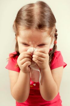 Little girl wipes her nose with a tissue.