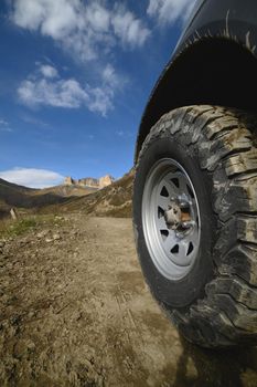 Big car wheel on mountains at day backdrop. Offroad 4x4 concept.