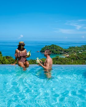 a young couple of men and women at a swimming pool during a vacation on a tropical island. man and woman in infinity pool during sunset. luxury vacation in Thailand pool of a luxury pool villa