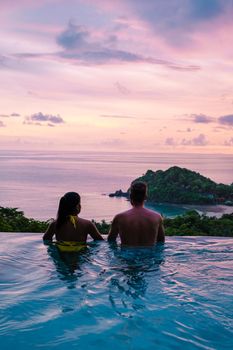 a young couple of men and women at a swimming pool during a vacation on a tropical island. man and woman in infinity pool during sunset. luxury vacation in Thailand pool of a luxury pool villa