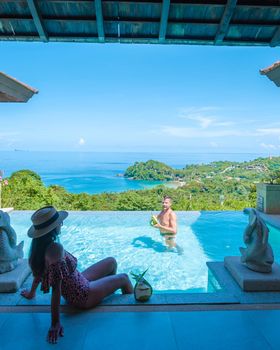 a young couple of men and women at a swimming pool during a vacation on a tropical island. man and woman in infinity pool during sunset. luxury vacation in Thailand pool of a luxury pool villa