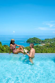 a young couple of men and women at a swimming pool during a vacation on a tropical island. man and woman in infinity pool during sunset. luxury vacation in Thailand pool of a luxury pool villa