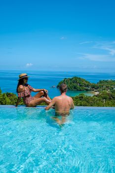 a young couple of men and women at a swimming pool during a vacation on a tropical island. man and woman in infinity pool during sunset. luxury vacation in Thailand pool of a luxury pool villa