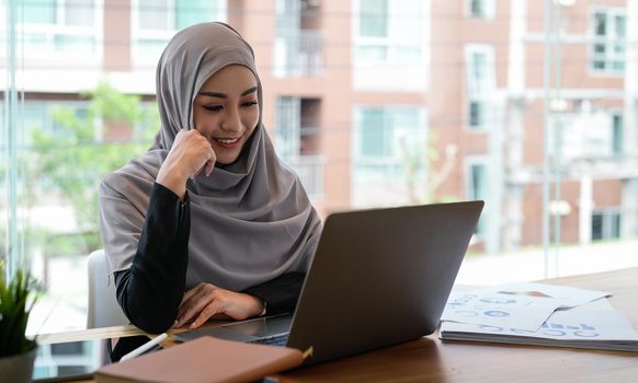 Muslim woman working with laptop computer in office , writing paper. Confidence pretty muslim woman Business and finance concept
