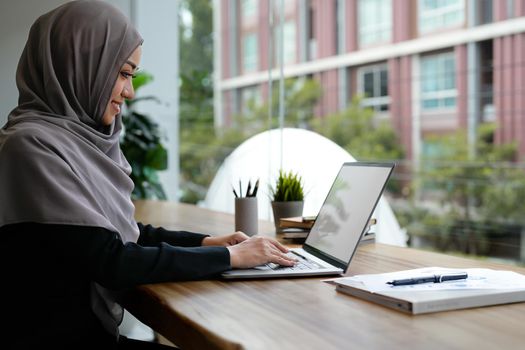 Happy beautiful muslim business woman brown hijab working about financial with business report modern office.