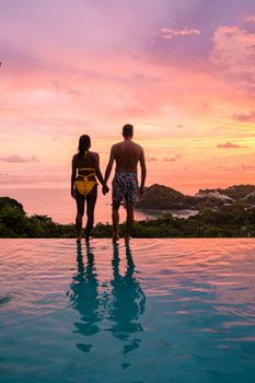 a young couple of men and women at a swimming pool during a vacation on a tropical island. man and woman in infinity pool during sunset. luxury vacation in Thailand pool of a luxury pool villa