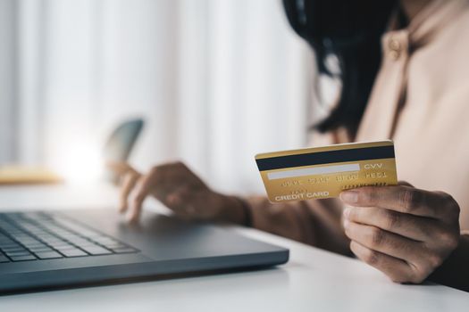 Close up of asian girl hold bank credit card and type on laptop, shopping online using computer, buying goods or ordering online, entering bank accounts and details in online banking offer