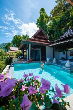 a young couple of men and women at a swimming pool during a vacation on a tropical island. man and woman in infinity pool during sunset. luxury vacation in Thailand pool of a luxury pool villa