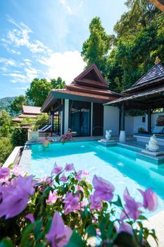 a young couple of men and women at a swimming pool during a vacation on a tropical island. man and woman in infinity pool during sunset. luxury vacation in Thailand pool of a luxury pool villa